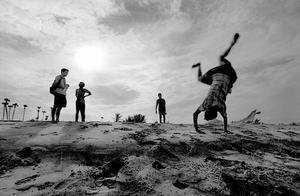 India, Mahabalipuram. July/31/2005.  Talking with boys on the beaches of Mahabalipuram, approximately 7 months after it was struck by the Tsunami. Although the Tsunami claimed lives, and most of the homes in their fishing village, life had more or less returned to the norm - including backflips into the ocean! Owen Murray © 2005